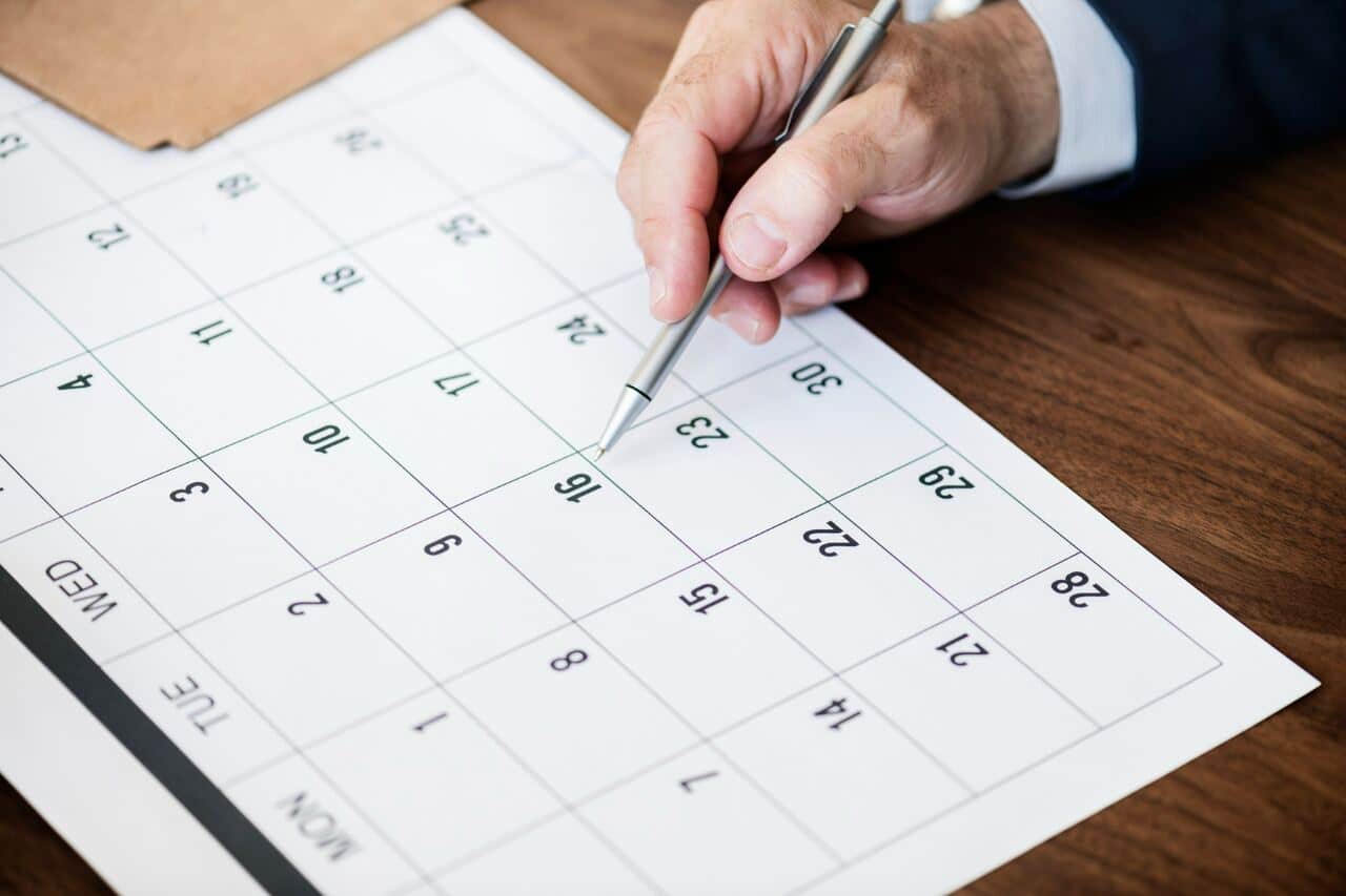 Hand marking a date on a calendar