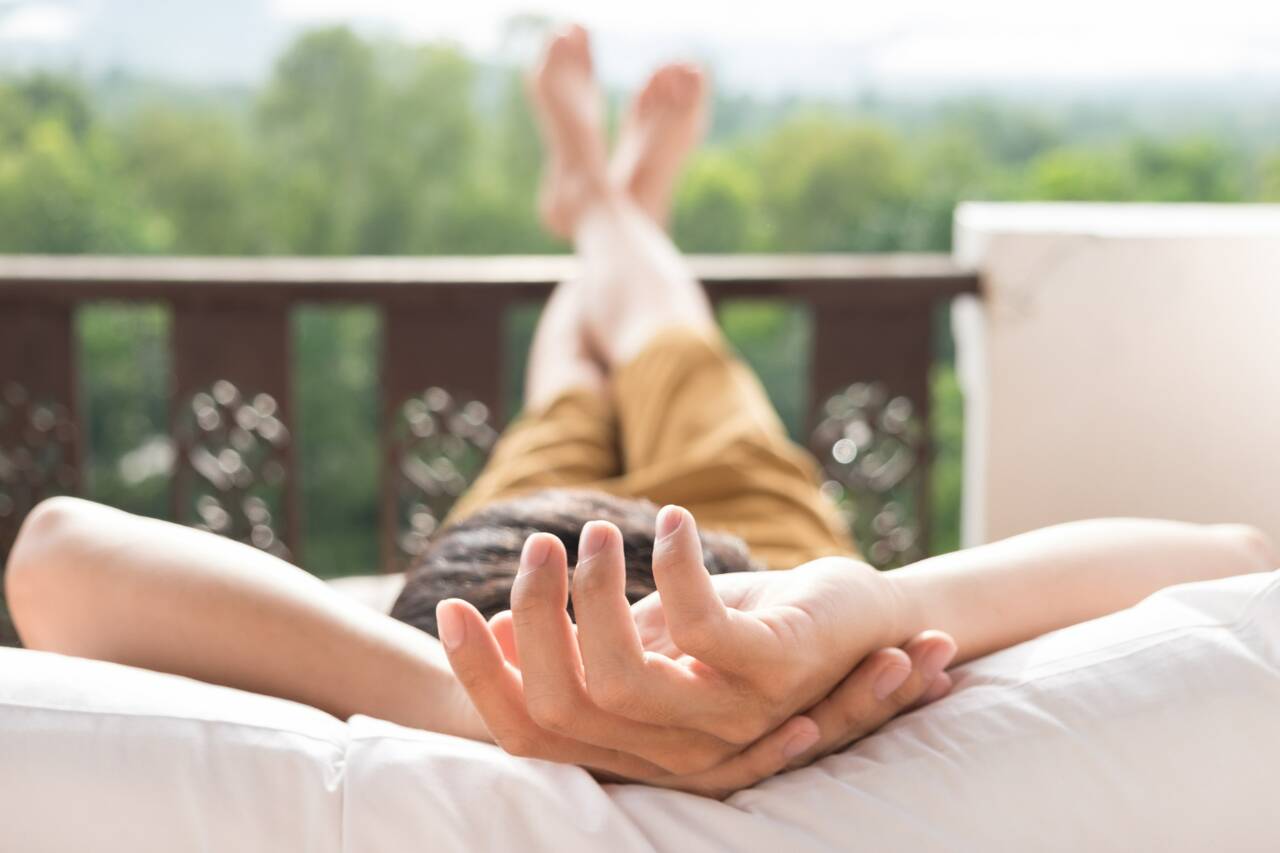 Person relaxing on a balcony with hands behind head