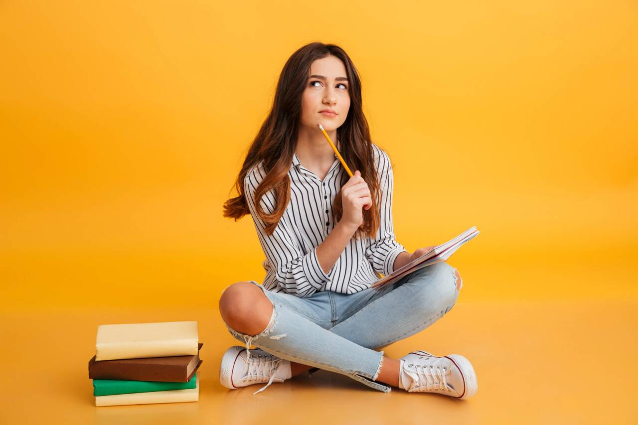 Woman holding a notebook and pencil while thinking