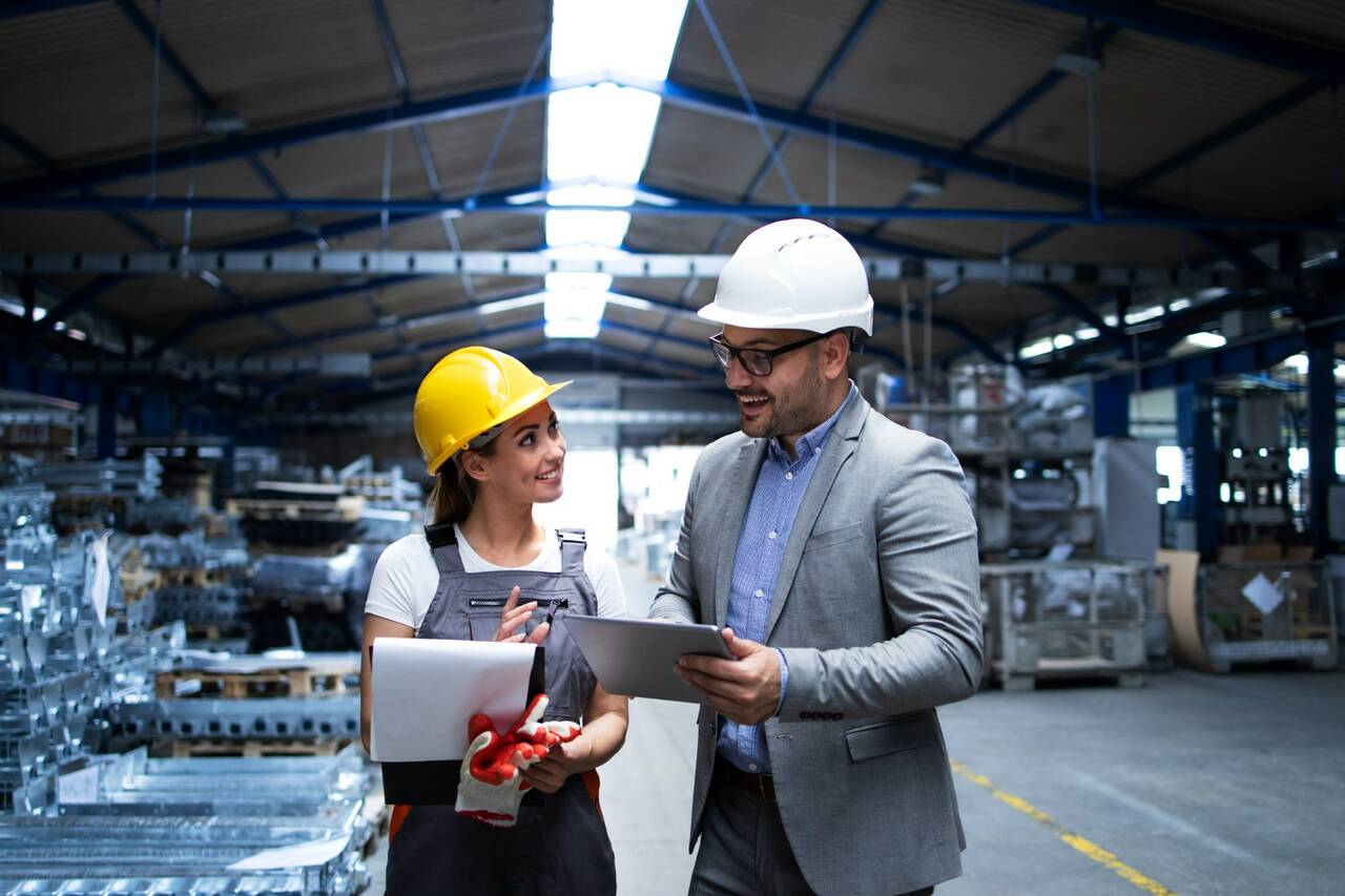 Two engineers with hard hats discussing in a factory