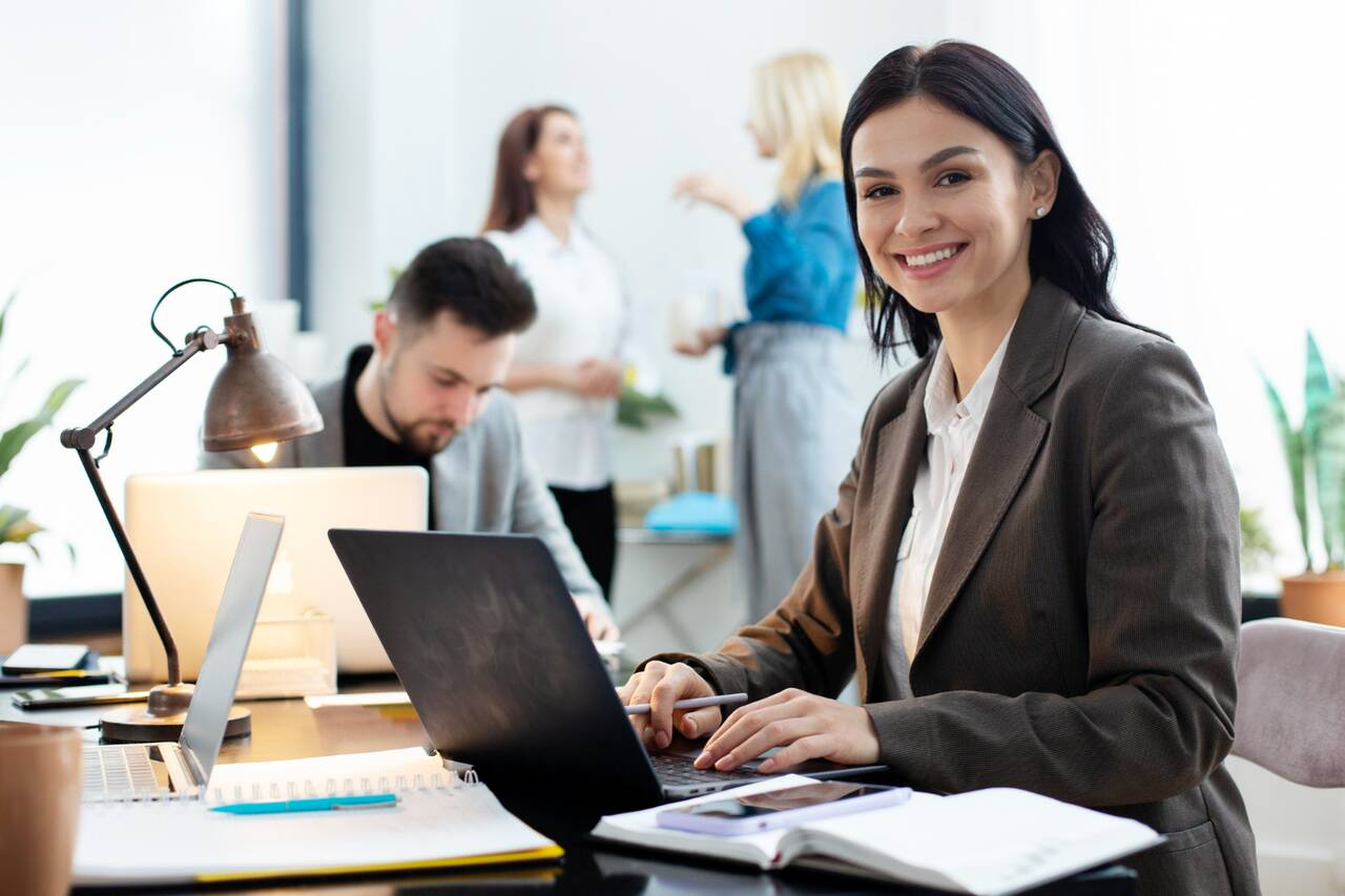 Woman working on a laptop in a busy office