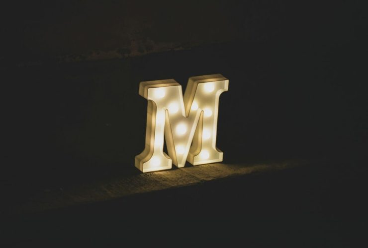 Illuminated letter "M" glowing in the dark