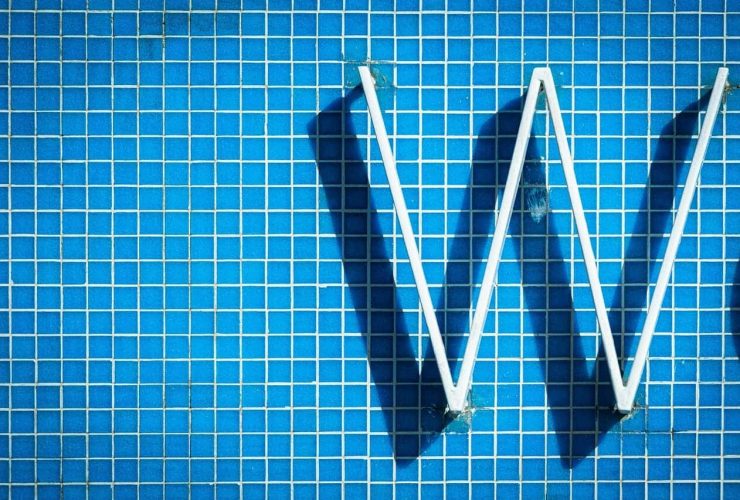 White letter "W" on a blue tiled wall.