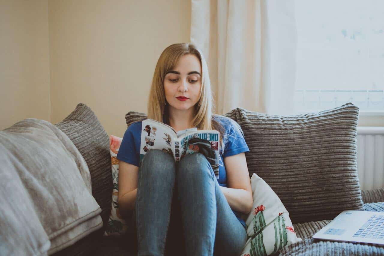 Woman sitting on a sofa reading a comic book