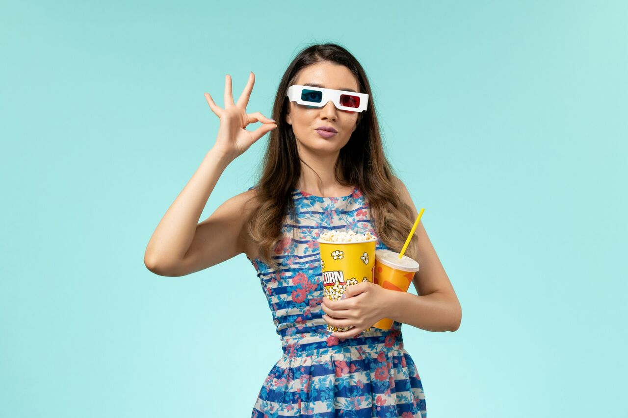 Woman wearing 3D glasses holding popcorn and drink