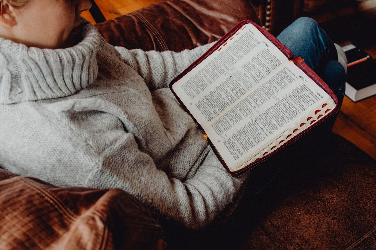 Person sitting on couch reading a large open book