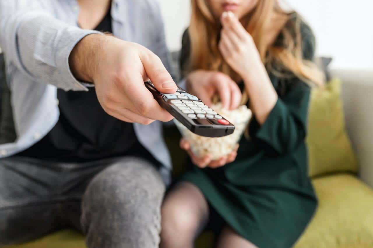 Person holding remote control with popcorn