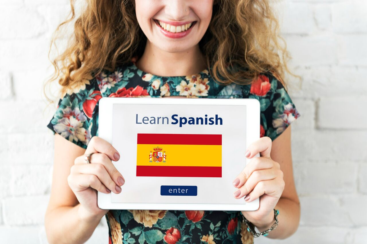 Woman holding tablet with Learn Spanish sign