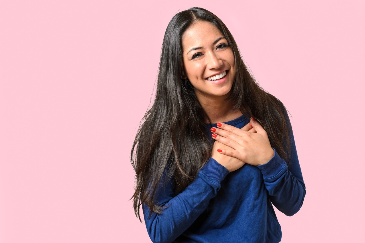 Smiling woman in blue shirt with hand on chest