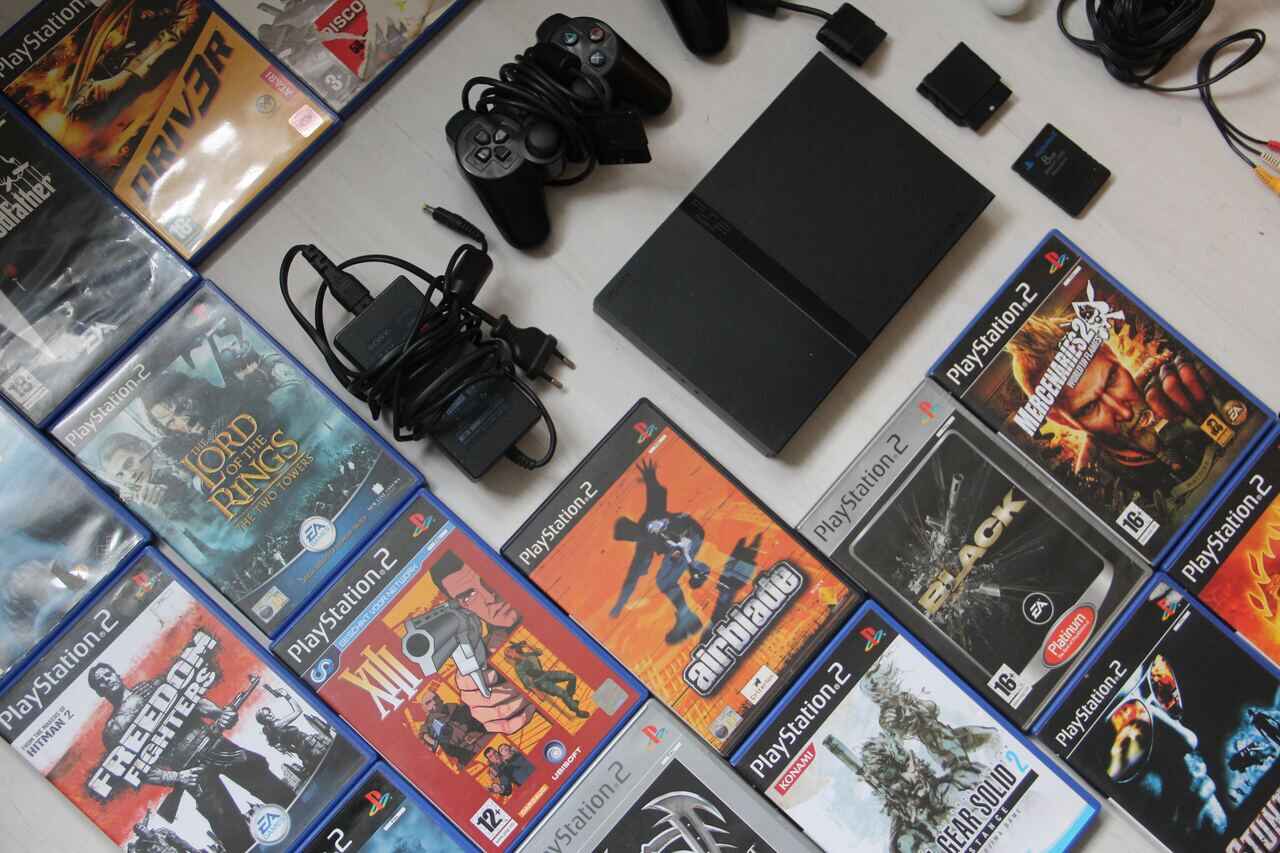 PlayStation 2 console, controllers, and various game discs laid out.