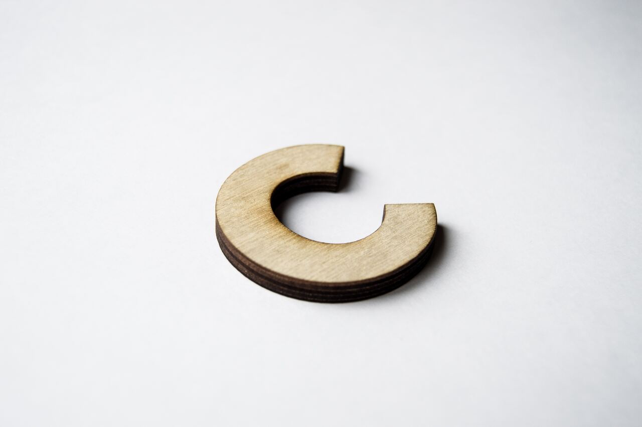 Wooden cutout of the letter C on white background