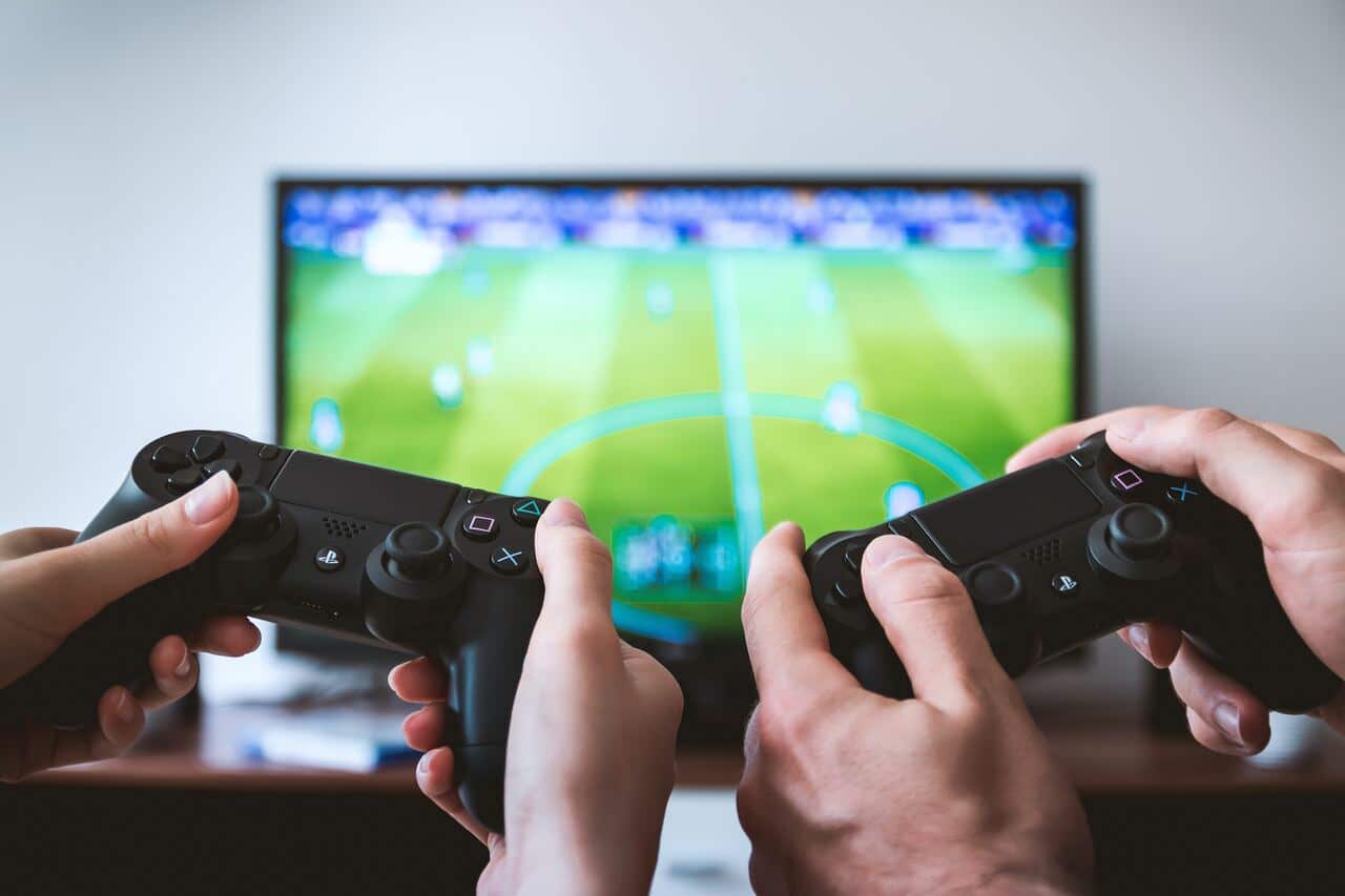 Two people playing a soccer video game using PlayStation controllers.