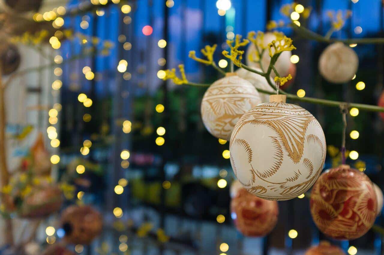 Hand-painted ornaments hanging with warm lights in the background