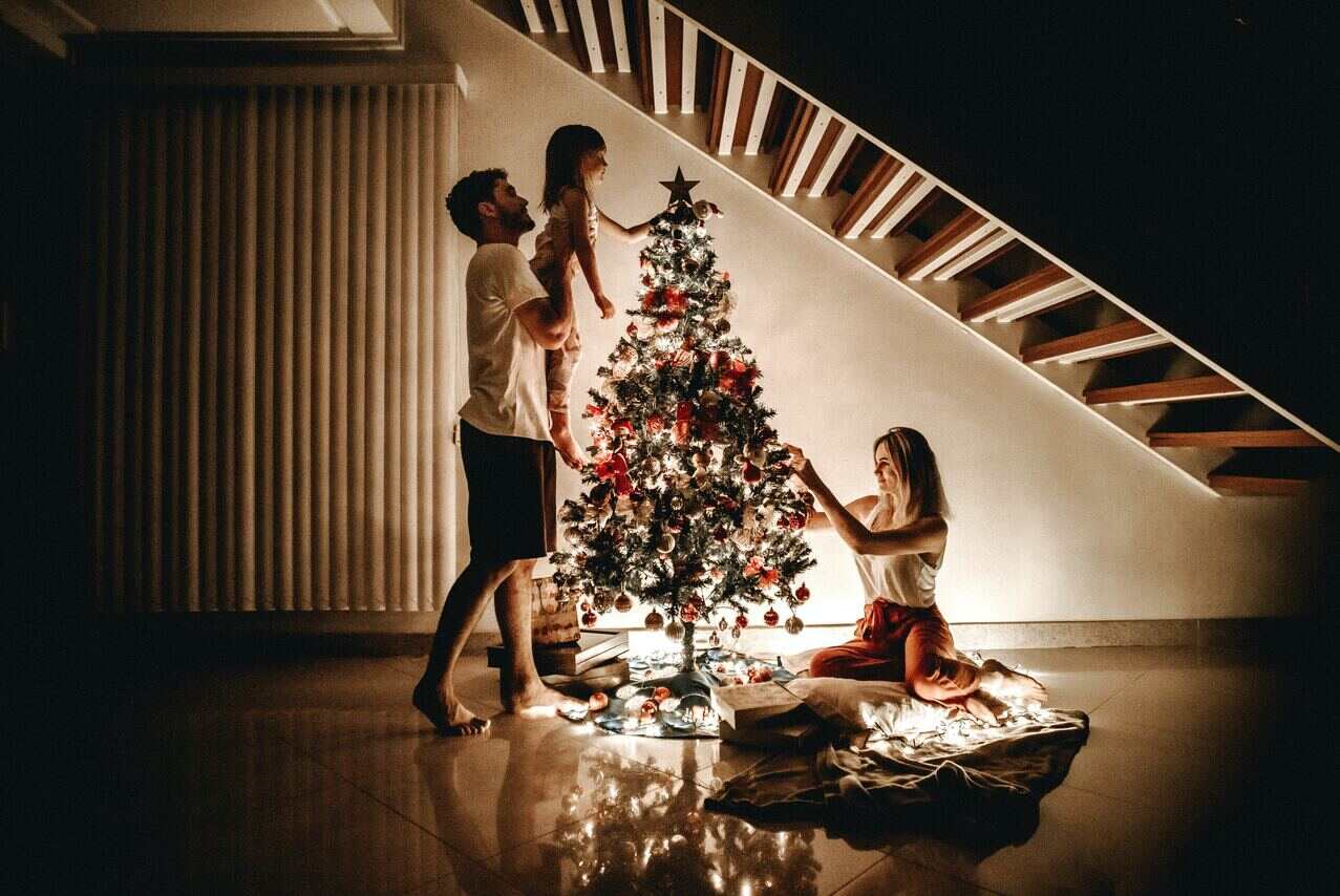 Family decorating Christmas tree near staircase