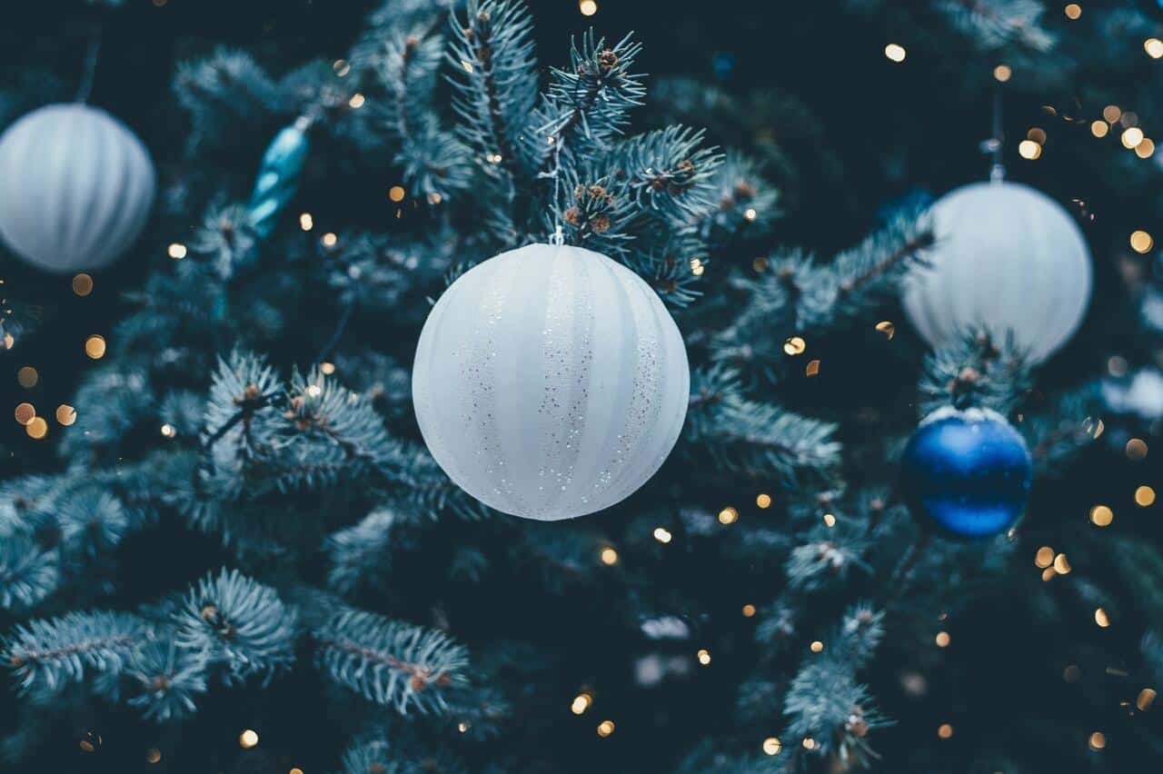 White Christmas ornaments hanging on a decorated tree