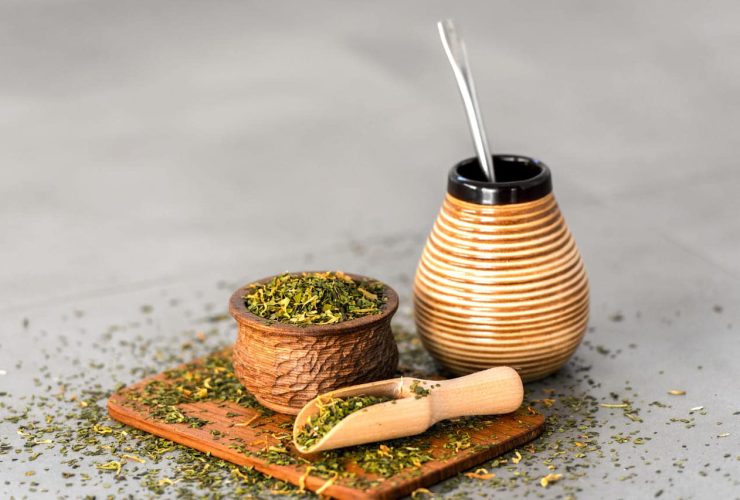 Yerba mate tea leaves in wooden bowl with traditional mate cup