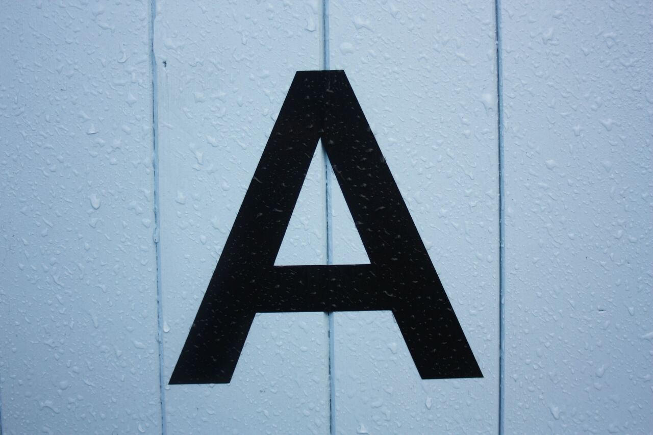 Black letter A on a white wall with raindrops