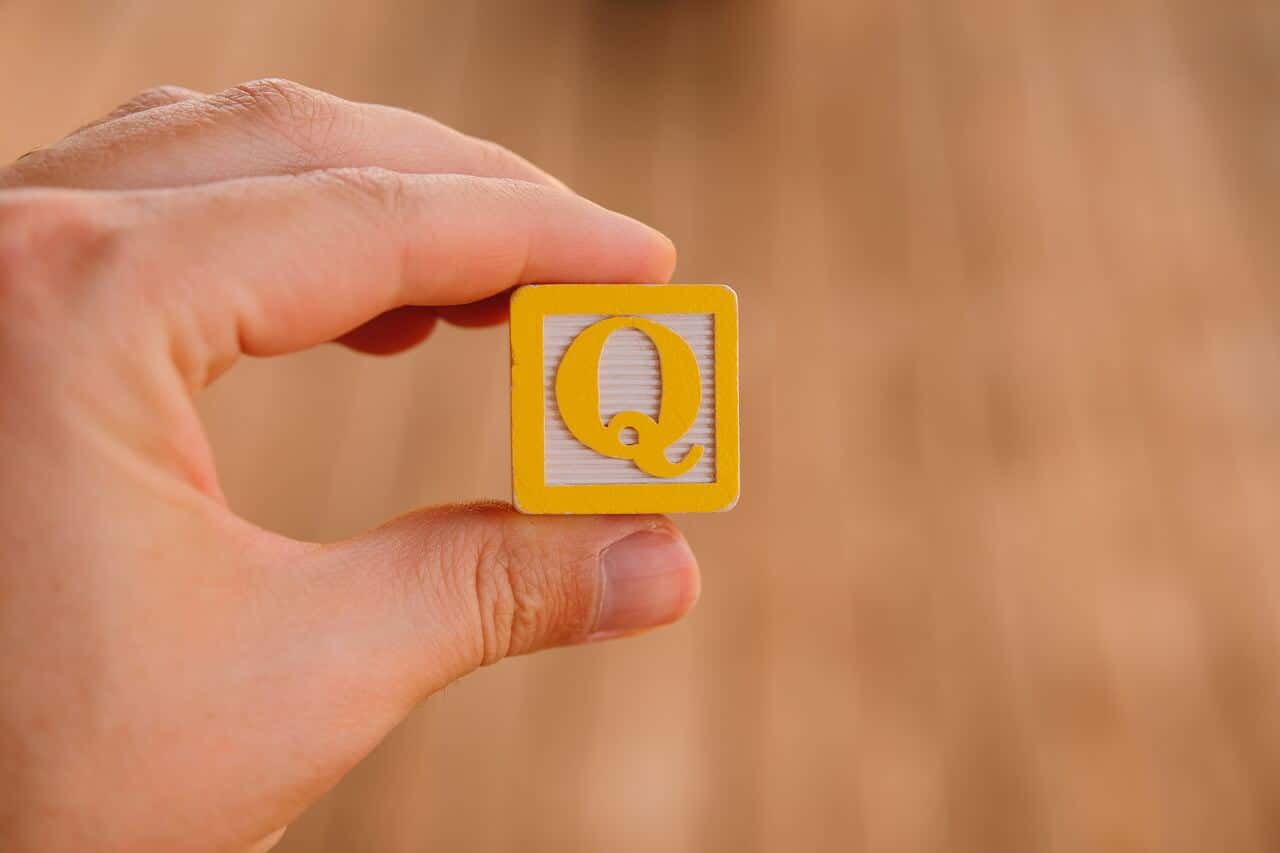 Hand holding yellow block with letter Q