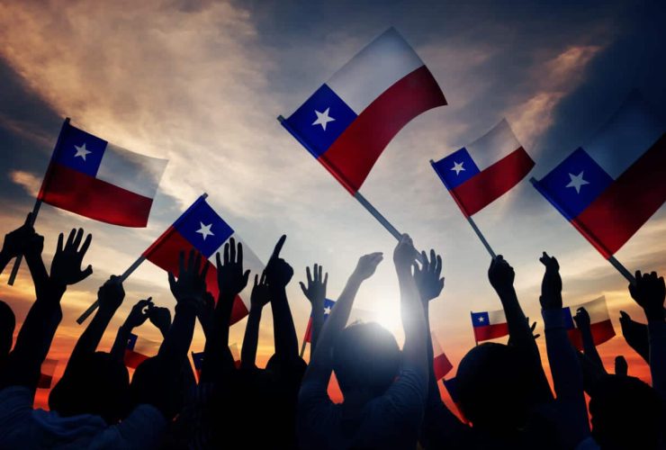 Silhouettes waving Chilean flags during sunset celebration