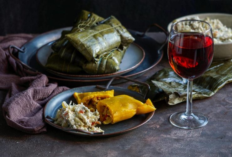 A plate of tamales and salad next to a glass of wine.