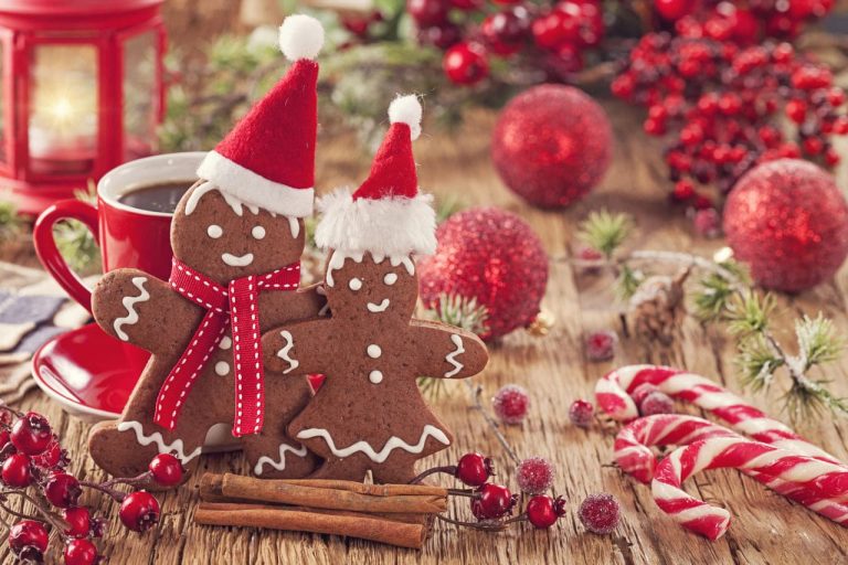 Two gingerbread cookies with Santa hats next to Christmas decorations