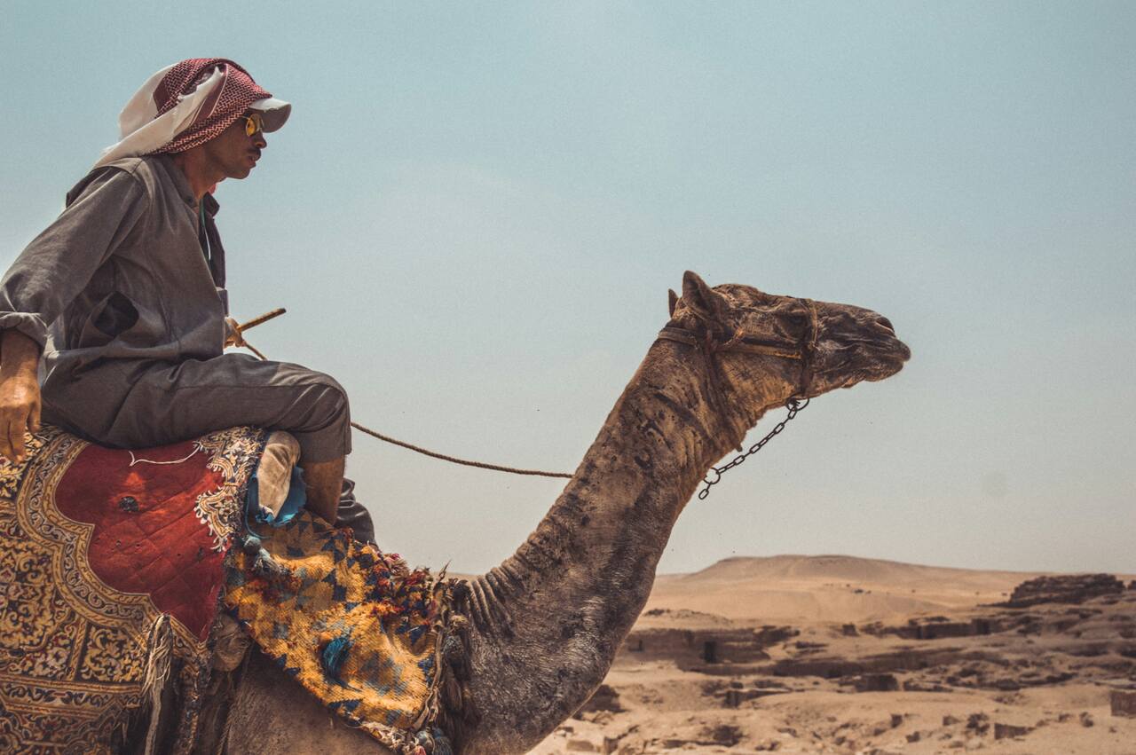 A man riding a camel in a deser